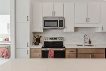 A kitchen with a stove, oven, microwave, and cabinets.